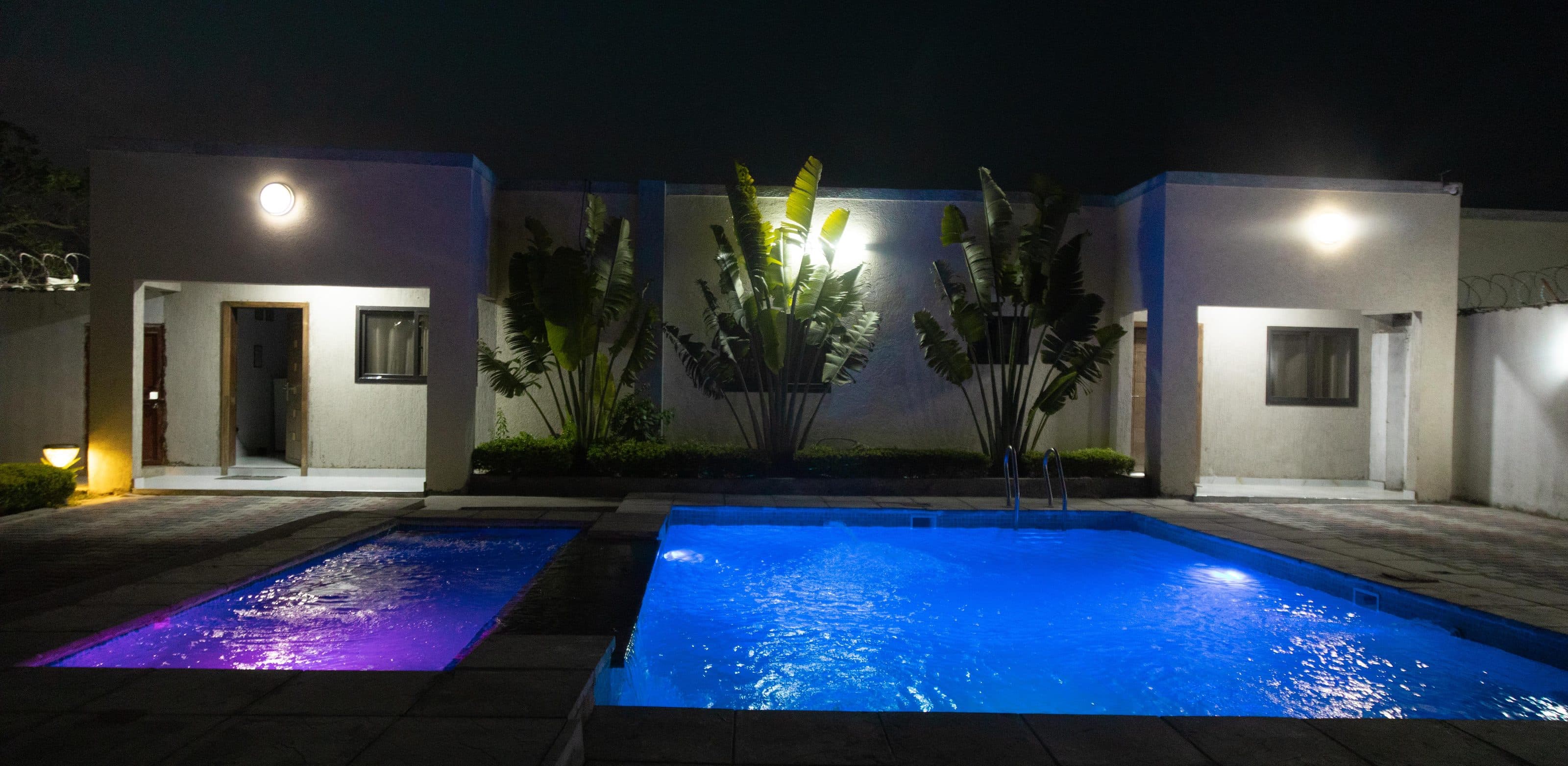 The shared pool lit up at night, with two of the apartments behind it